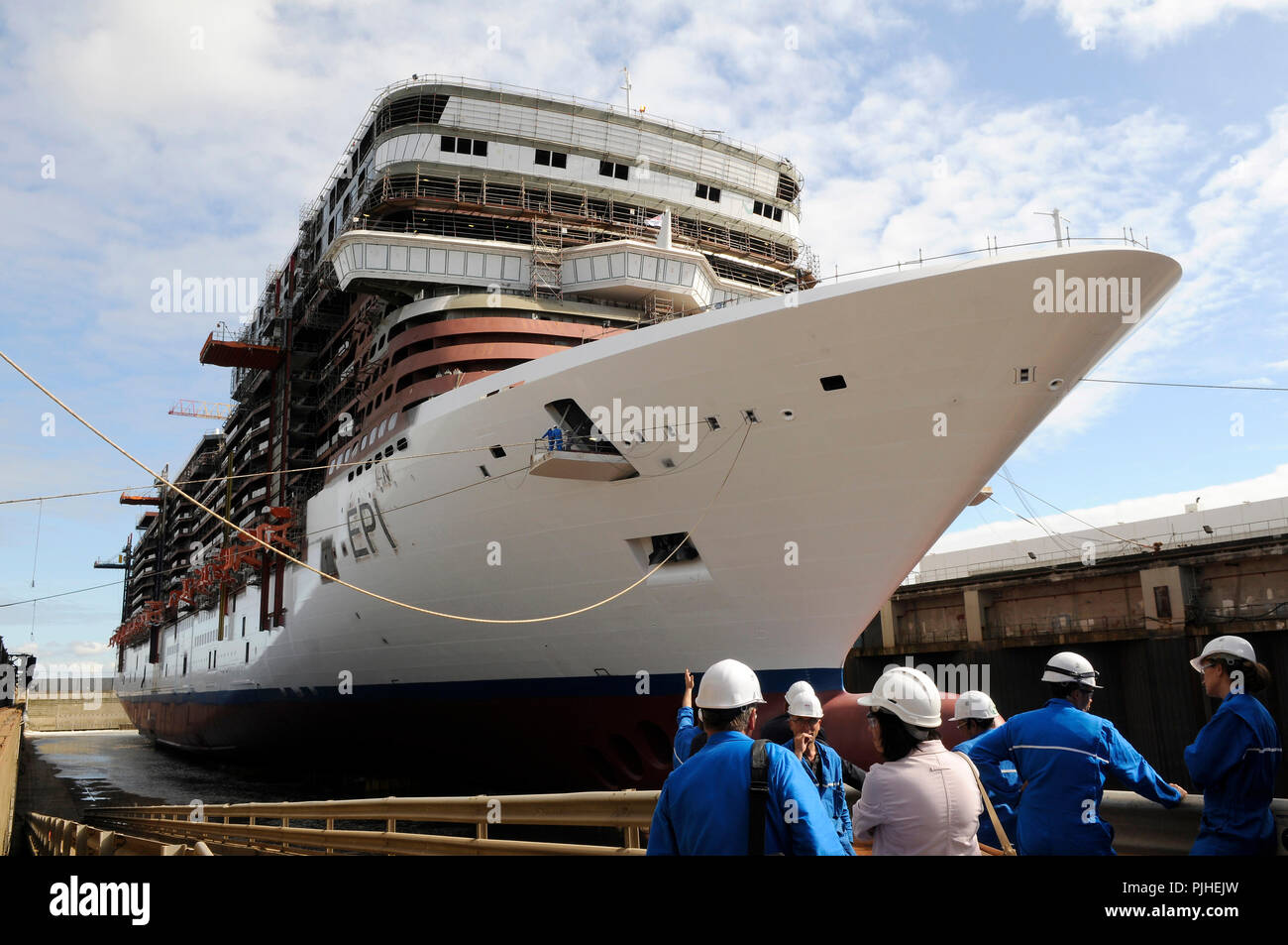 France, STX Europe shipyard in Saint-Nazaire city, Norwegian Epic cruise ship being built for the US company NCL, employees man and woman in the foreground, western France. Stock Photo