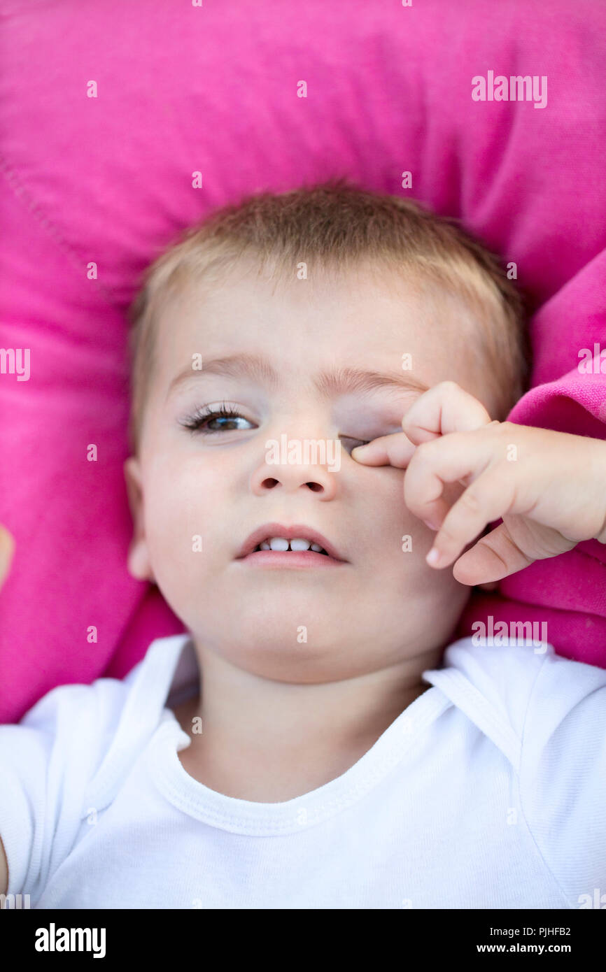 Closeup of a tired baby rubbing his eyes Stock Photo Alamy