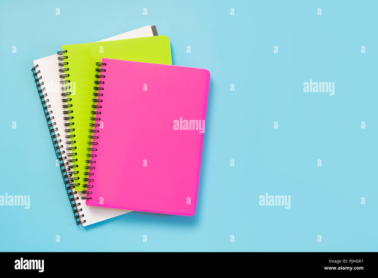 Colorful girlish school supplies, notebooks and pens on punchy blue. Top view, flat lay. Copy space. Stock Photo