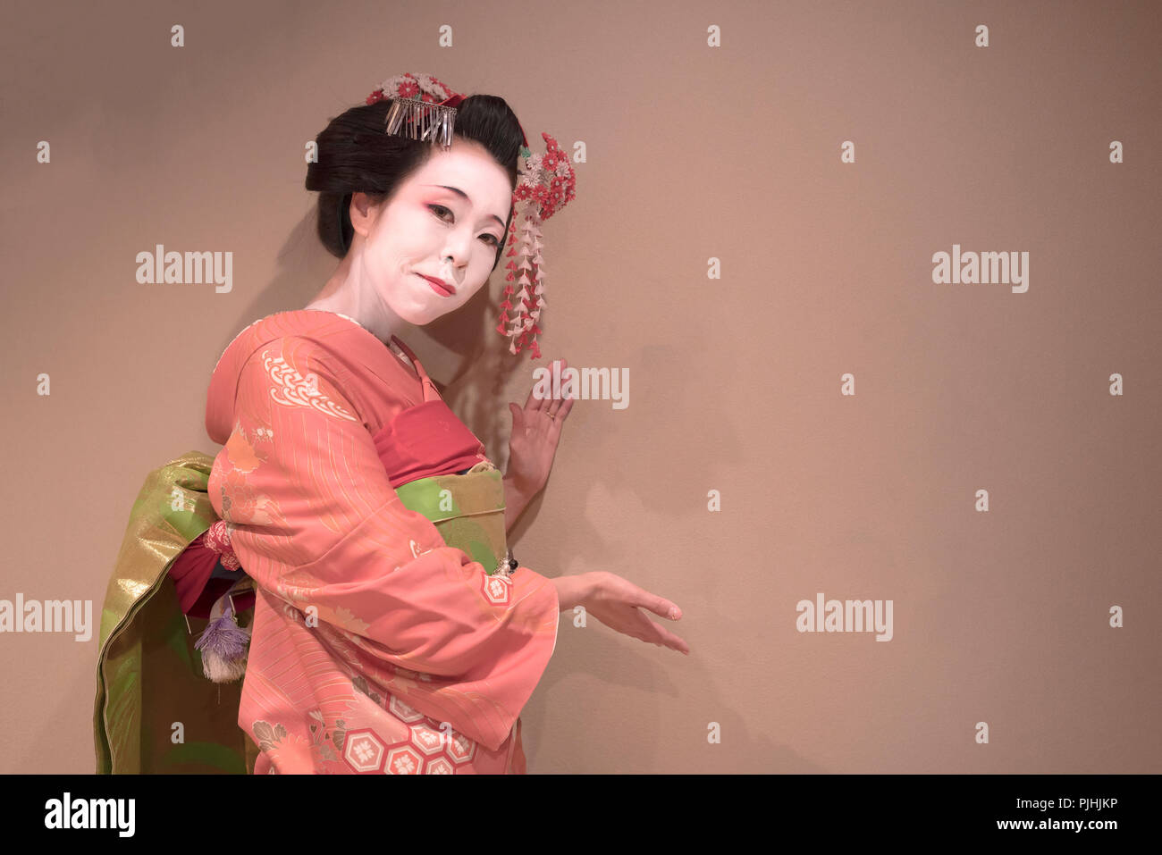 Clipping japanese geisha maiko girl in red kimono coifed hair brooch with patterns of red and white plum blossoms on white background. Stock Photo