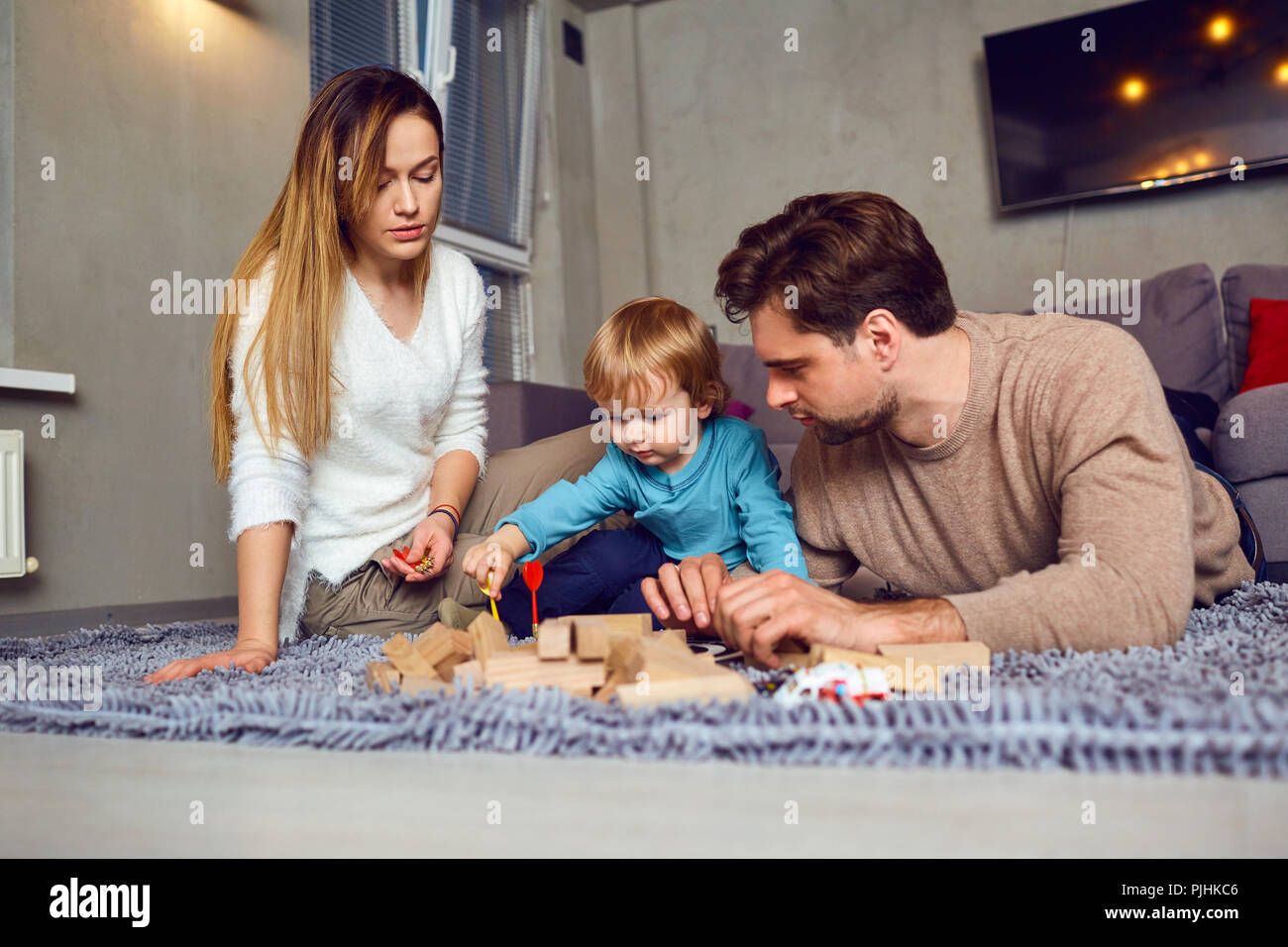 A family with a child plays board games indoors Stock Photo