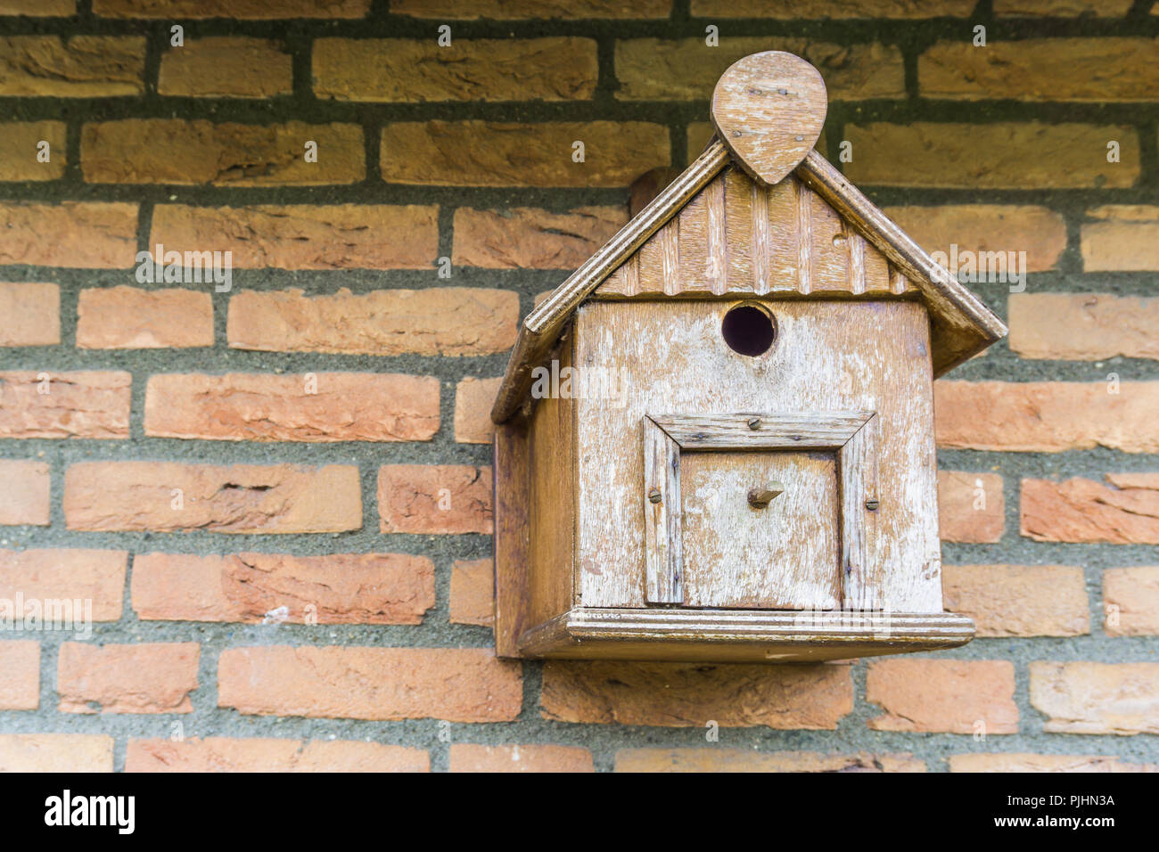 Hand crafted wooden bird house shelter for birds hanging on a brick wall Stock Photo