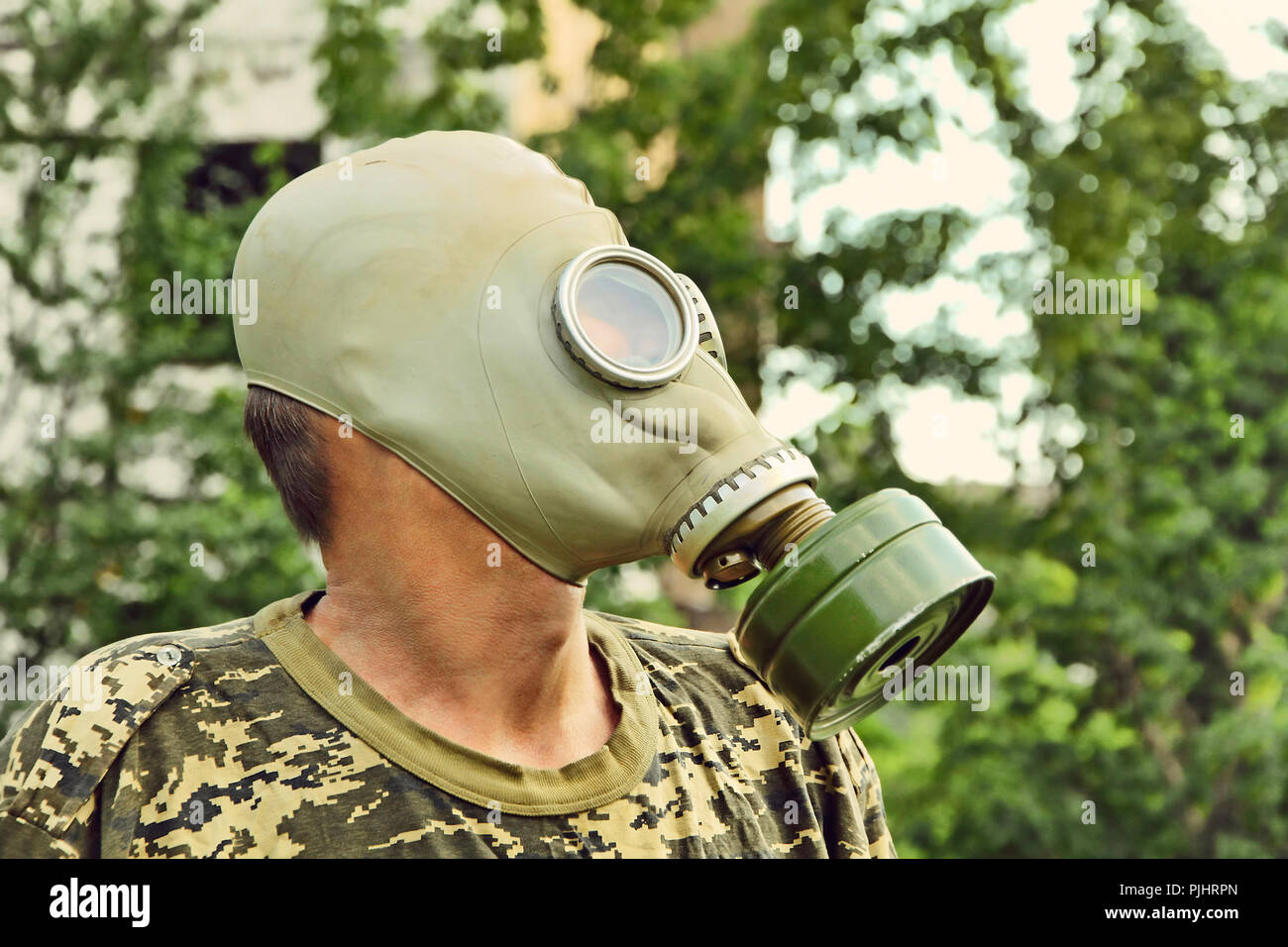Men in gas mask taken closeup on overgrown urban background