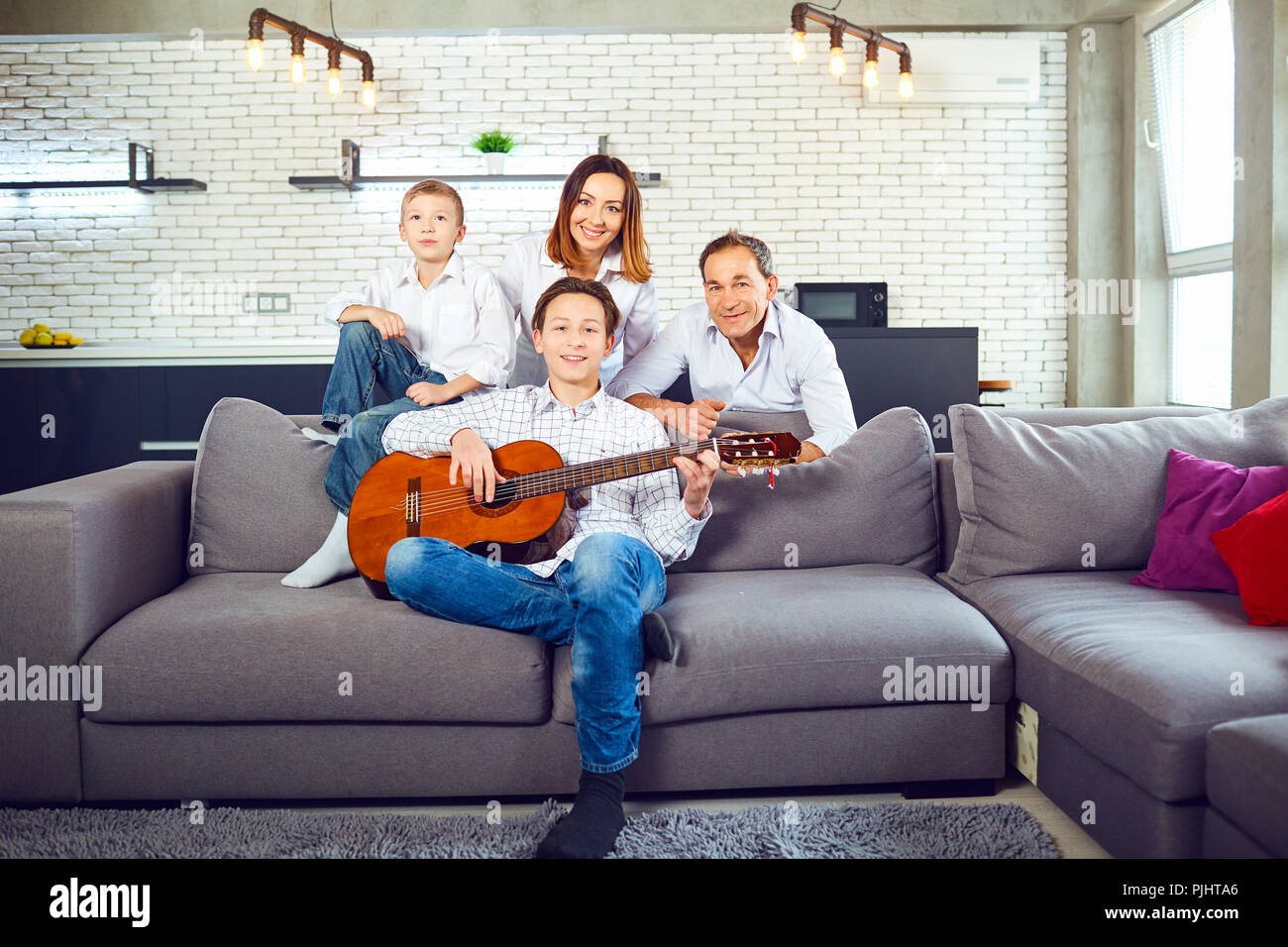 Happy family with guitar singing songs in the room. Stock Photo