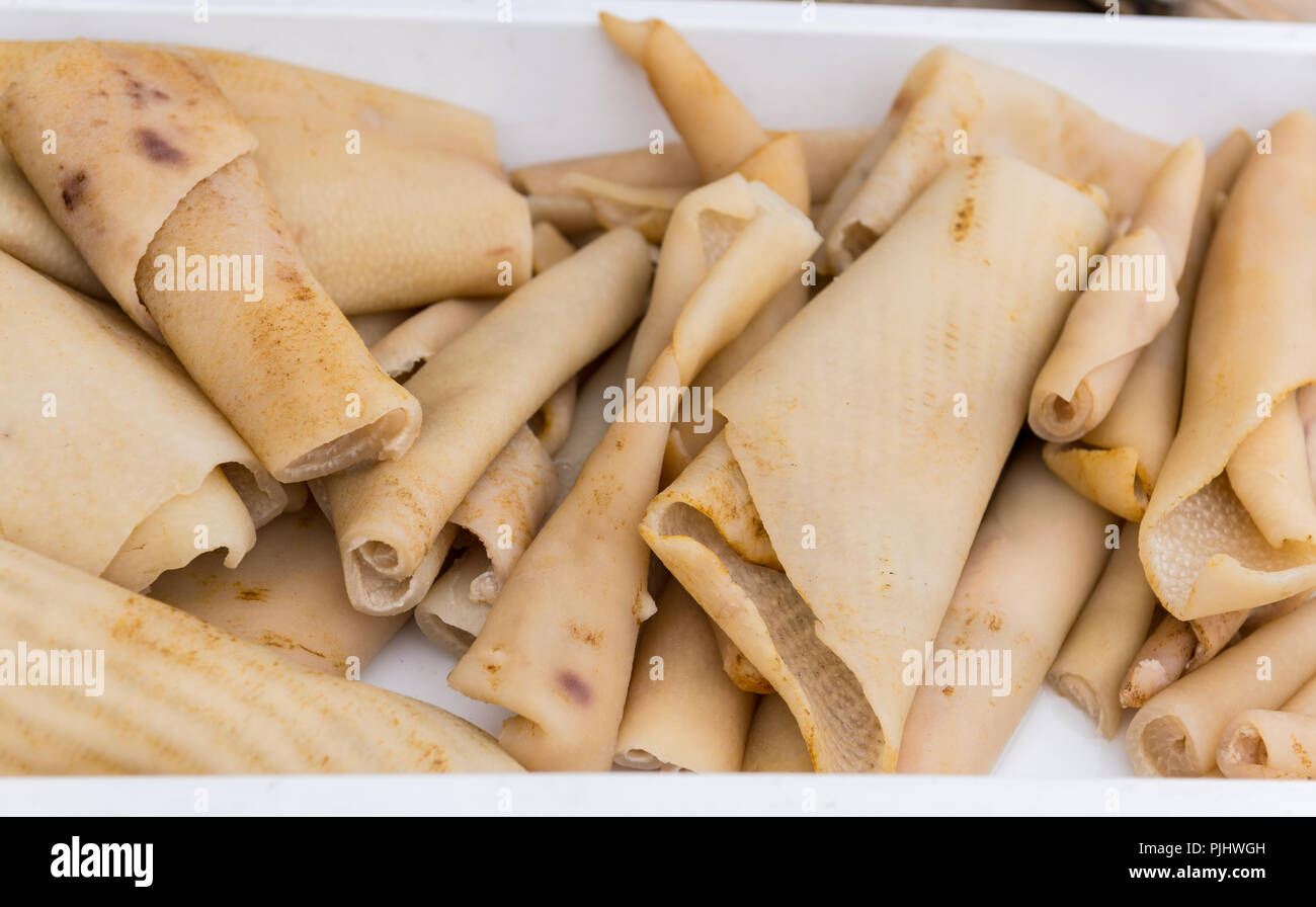 Close up of raw pork skins or pork rind which can be eaten as is or fried or roasted in pork fat (lard) as a snack. Stock Photo