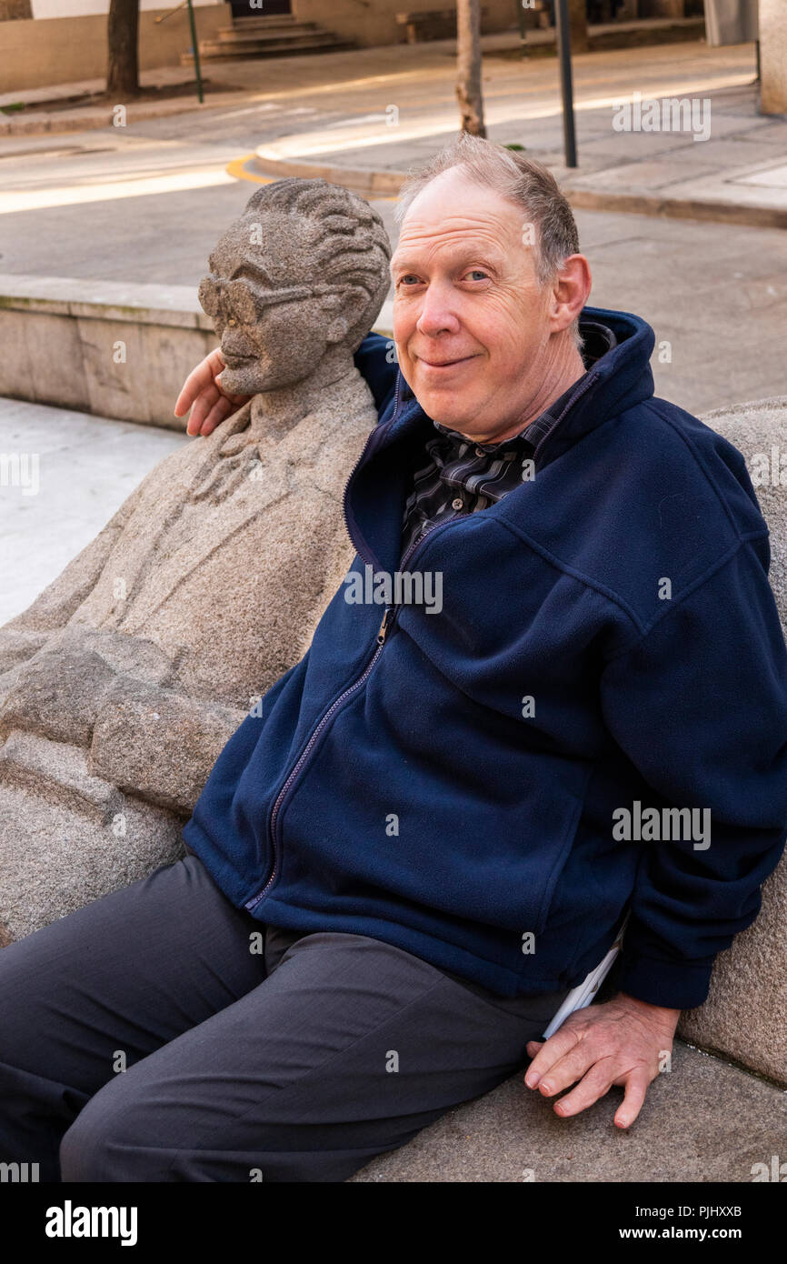 Spain, Galicia, A Coruna, Rua Pio XII, Prazo do Humor, disabled tourist sat next to sculpture on bench Stock Photo