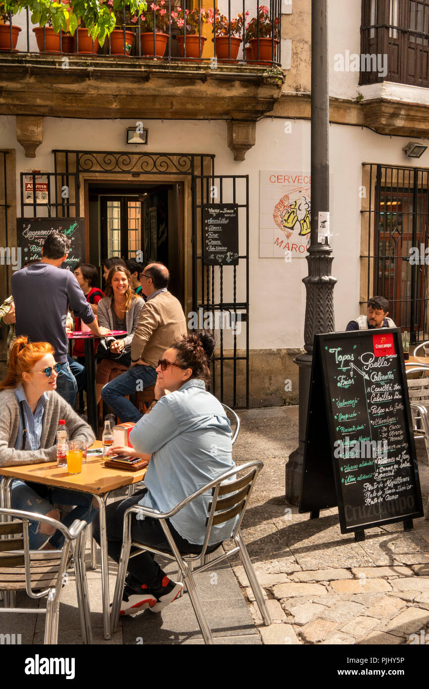 Spain, Jerez de La Frontera, Plaza de Abastos, customers sat at outside bar table in sunshine Stock Photo