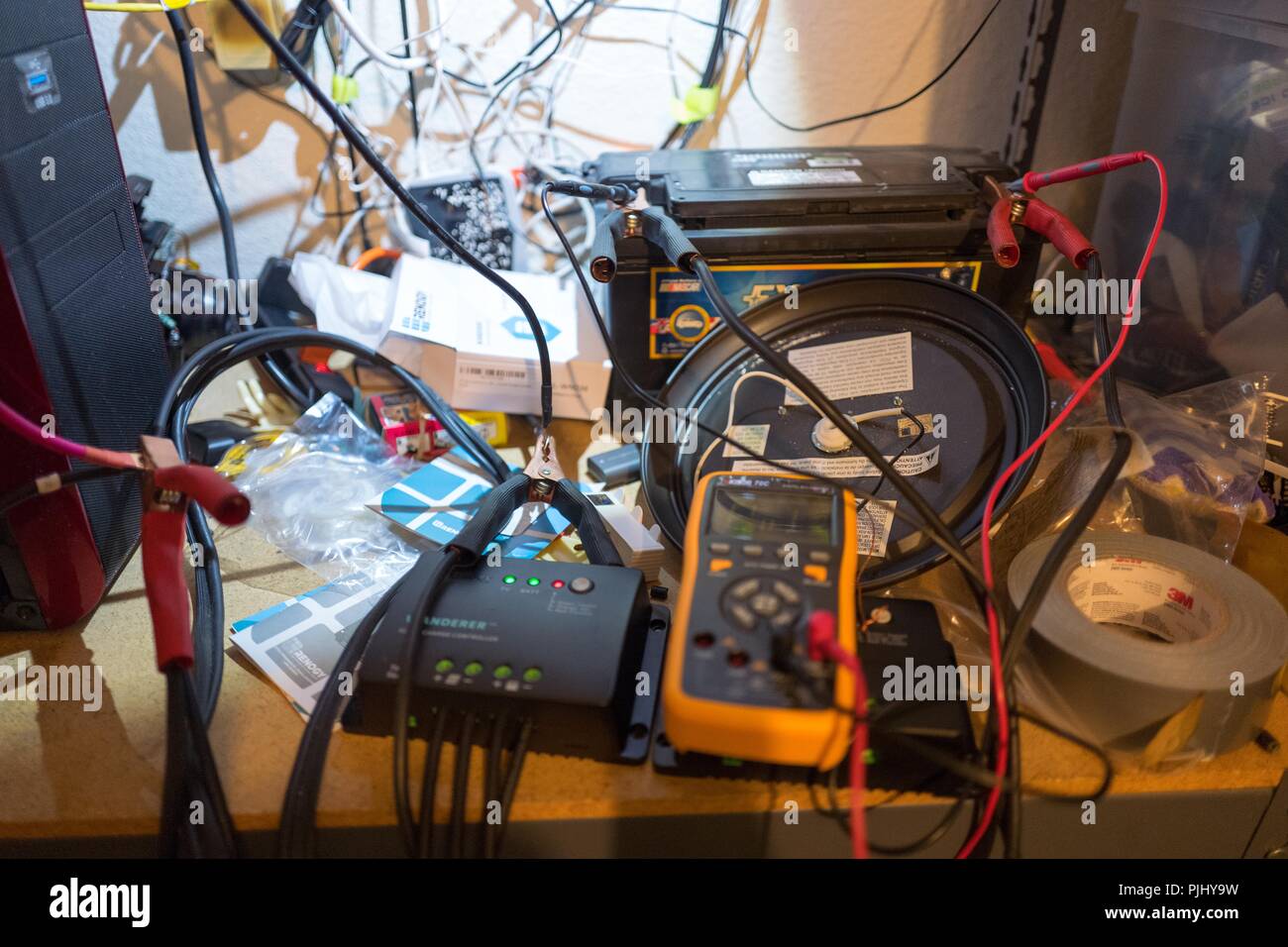 Cluttered electronics workshop with multimeter, battery, solar components and other electronics visible, September 6, 2018. () Stock Photo