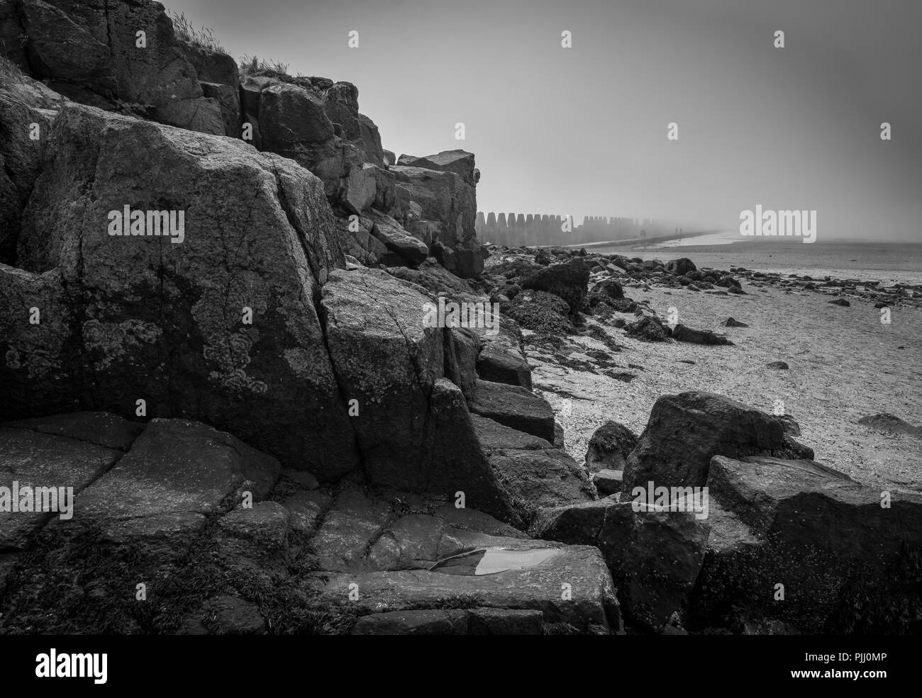 View from the rocks to the foggy anti-pylons by the beach. Stock Photo