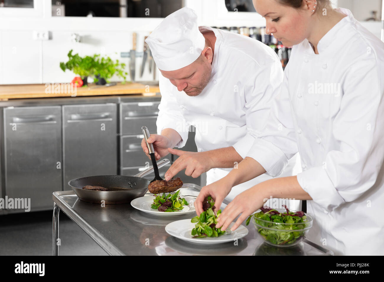 Two professional chefs prepares steak dish at gourmet restaurant Stock Photo