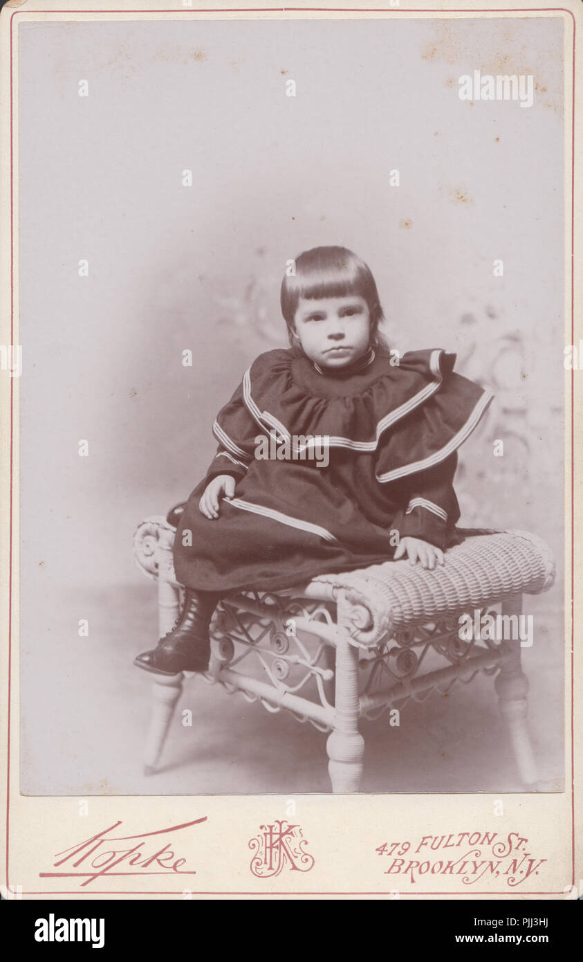 Victorian Brooklyn, New York Cabinet Card of a Young Child Sat on a Wicker Stool / Chair Stock Photo