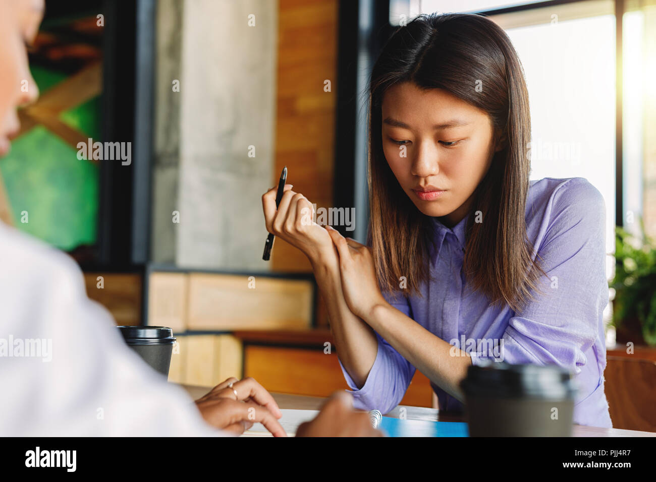 Two colleagues discussing in cafe, sitting at table Stock Photo
