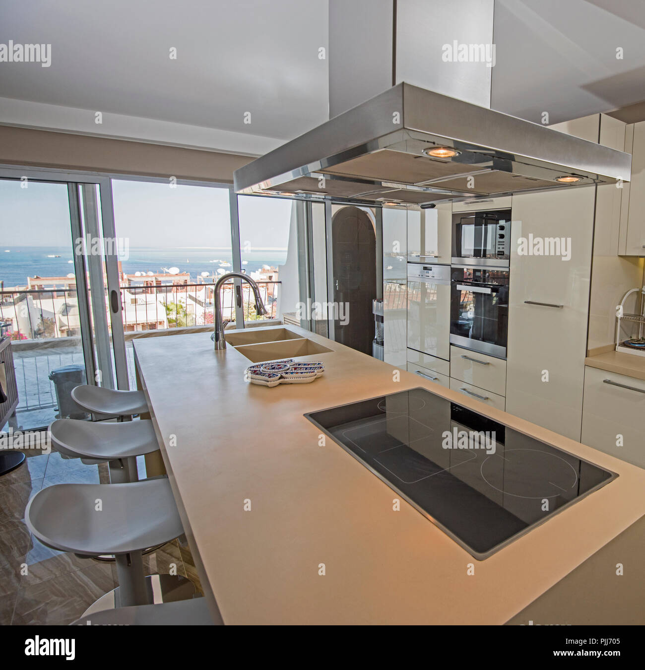 Interior design decor showing modern kitchen and appliances in luxury apartment showroom with sea view Stock Photo