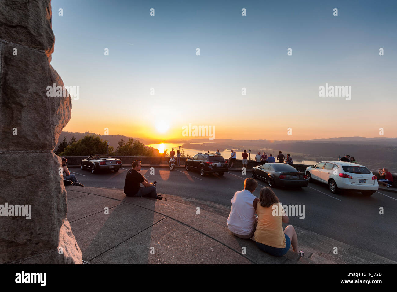Distant Forest Fires fill the air with smoke allowing a fiery sunset to be view by those gathered at Crown Point's Vista House in the Columbia River G Stock Photo