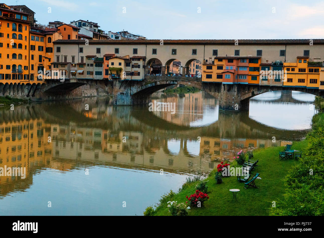 Ponte Vechio the most famous bridge and tourist attraction in Florence reflected in the Arno River's still waters with architecture along the river Stock Photo