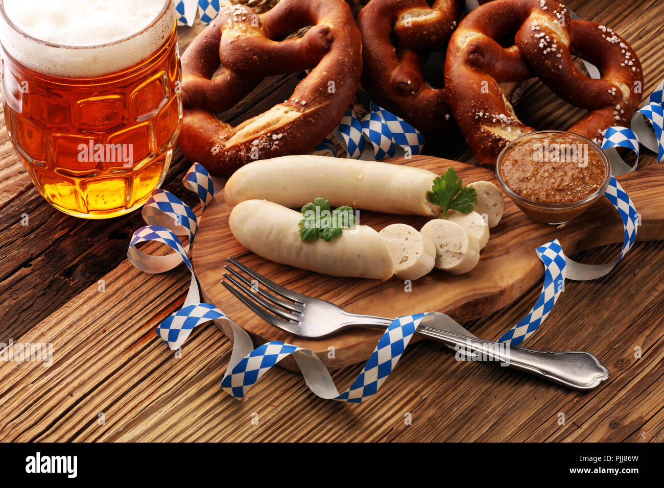 Bavarian veal sausage breakfast with sausages, soft pretzel and mild mustard on wooden board from Germany. Stock Photo