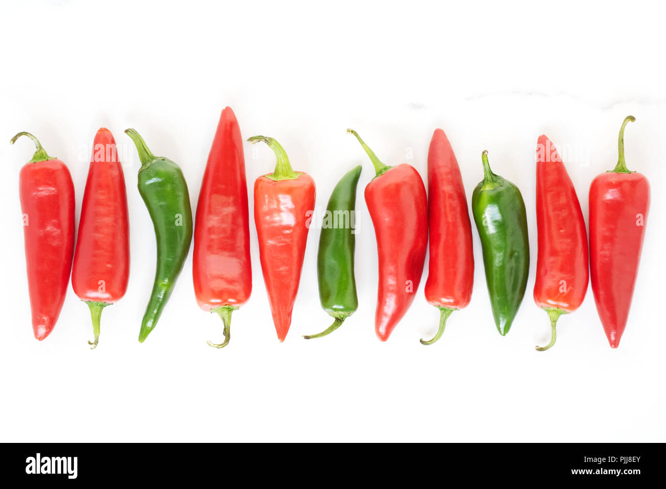 Capsicum annuum. A row of red and green chilli peppers. Stock Photo