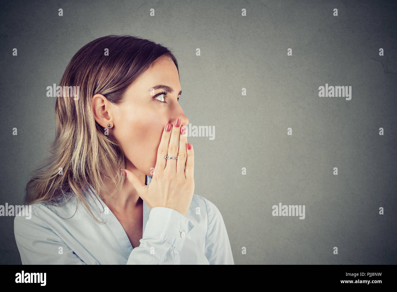 Young woman covering mouth while gossiping and telling secrets in whisper. Stock Photo