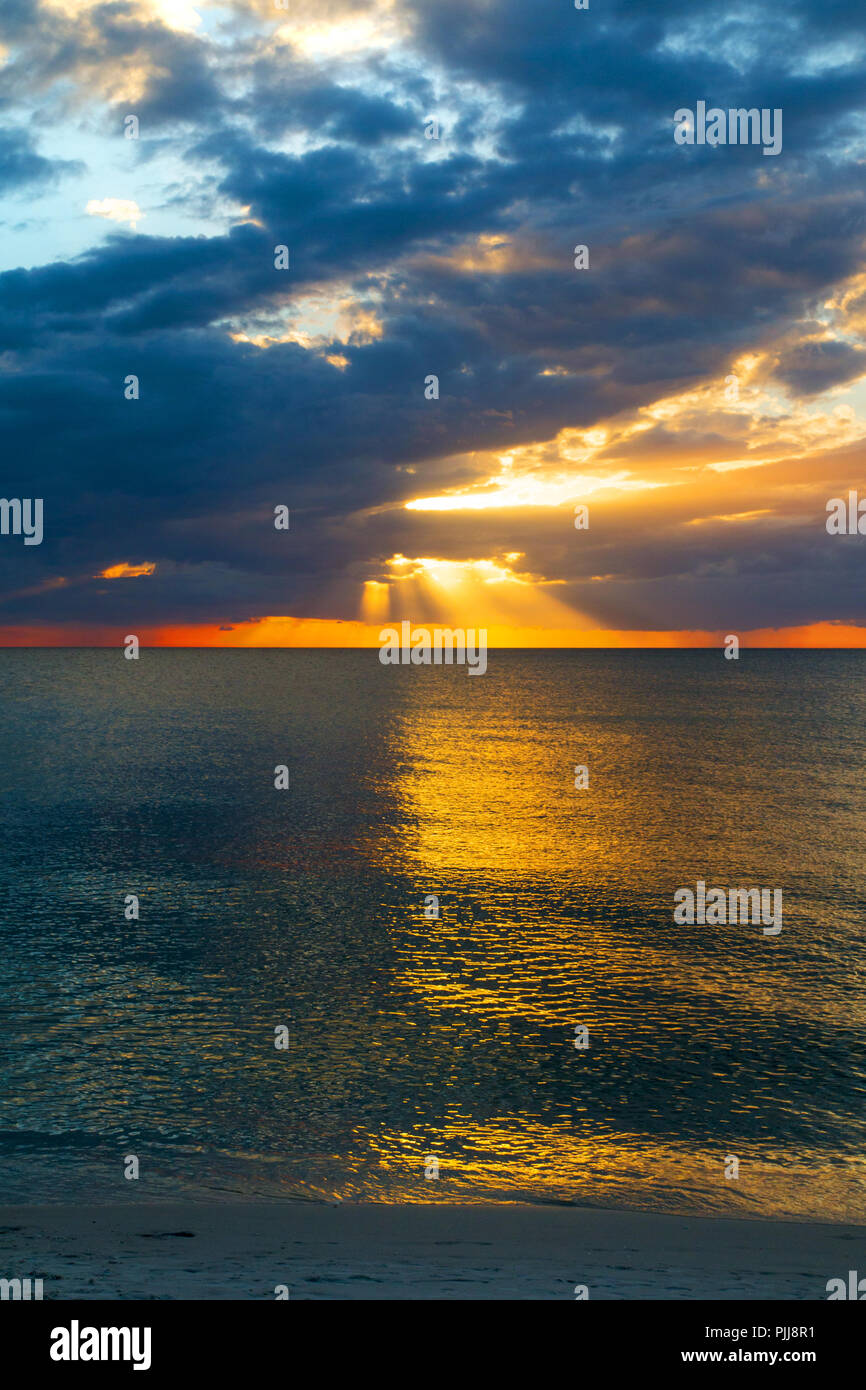 Colourful sunset sky with golden sun rays above the blue sea of ...
