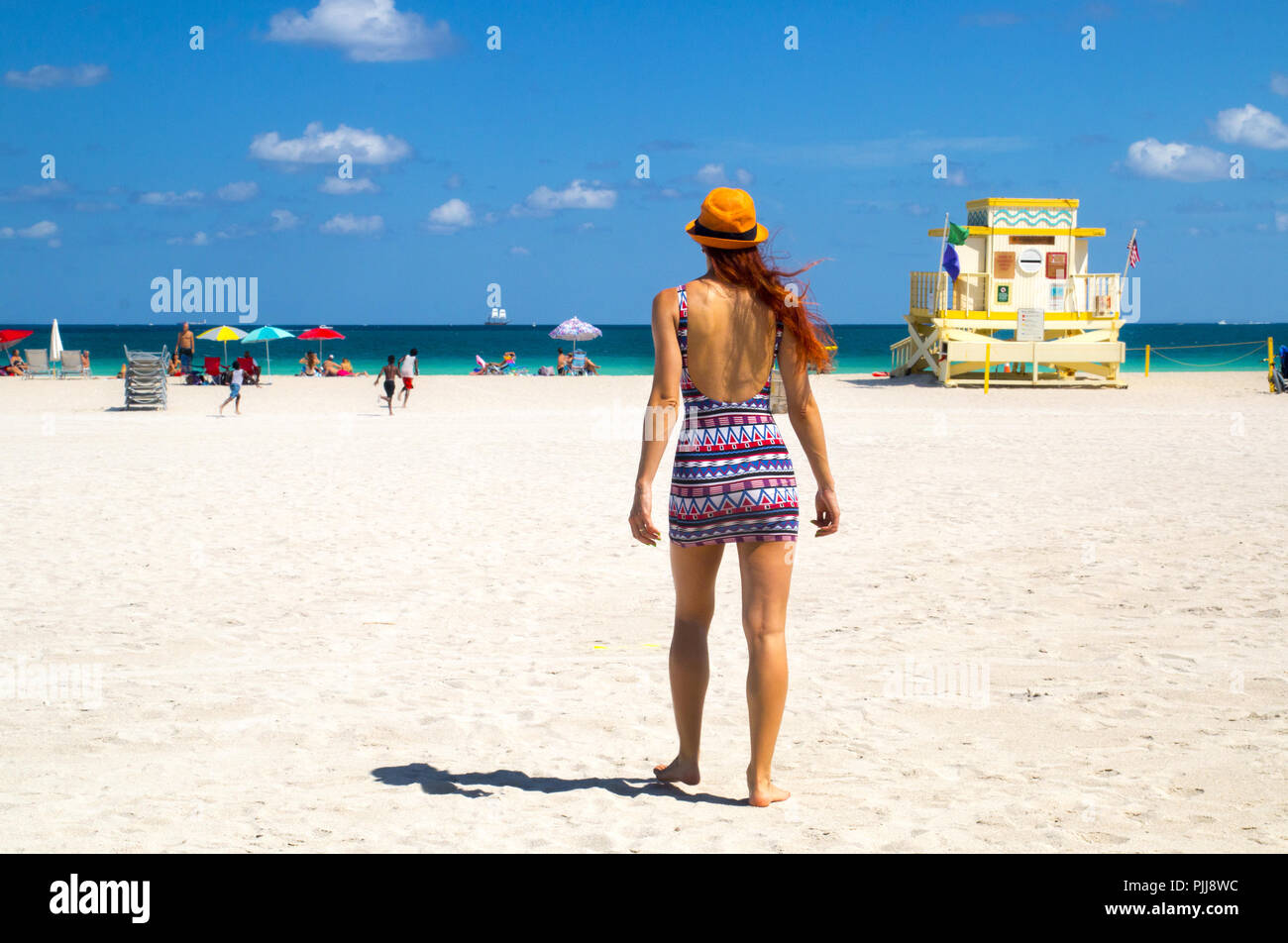 Holiday at Miami Beach Florida. Back view of red hair woman in fashionable  style summer outfit, lifeguard tower, children and sunbathing people, USA  Stock Photo - Alamy