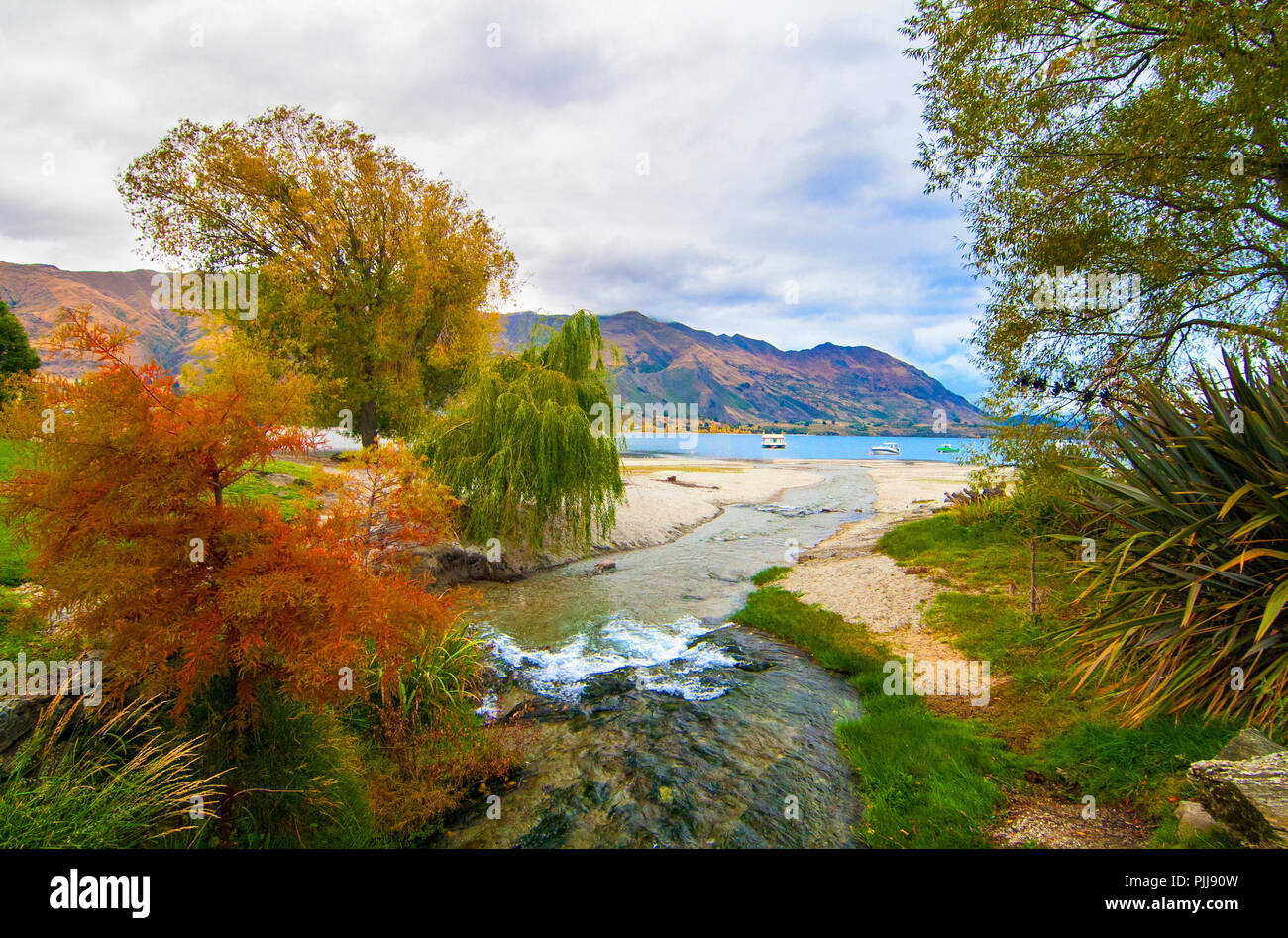 Autumn colours at Lake Wanaka in Central Otago region of New Zealand, river stream, lake and hills at the background Stock Photo