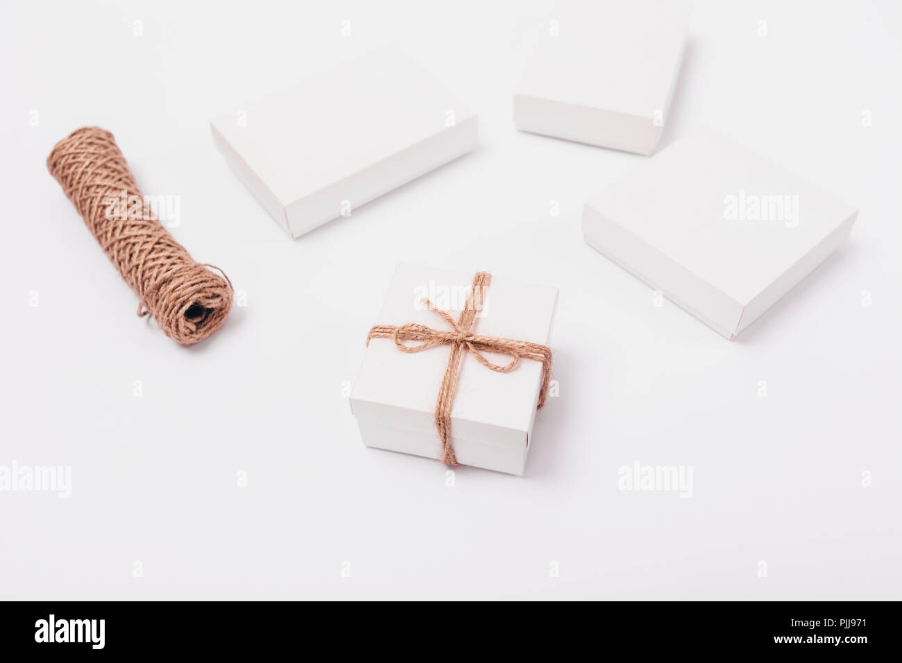 https://c8.alamy.com/comp/PJJ971/packaging-gifts-jute-rope-minimalistic-stylish-composition-of-small-gift-box-next-to-twine-coil-and-simple-white-presents-PJJ971.jpg