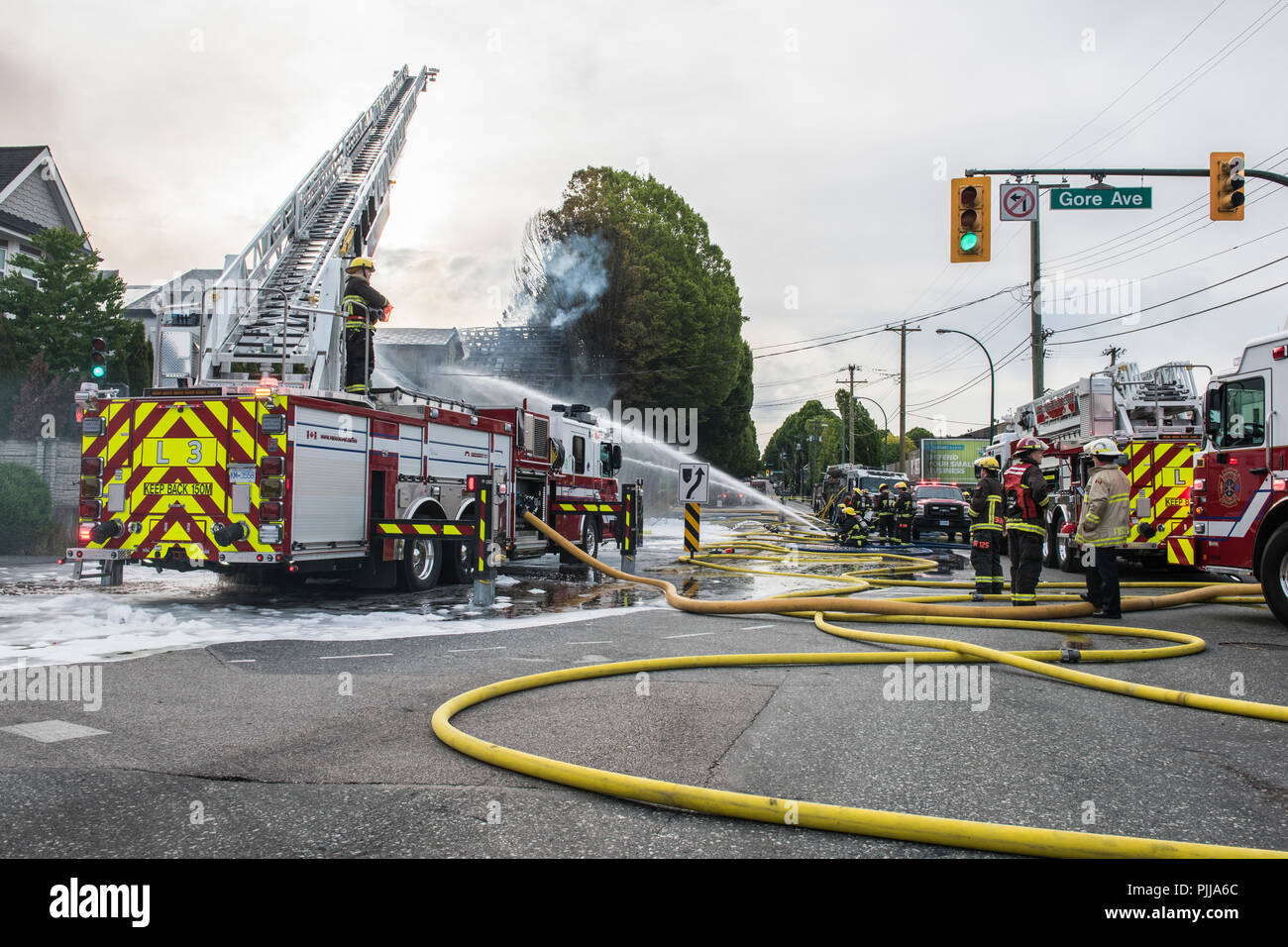 Emergency personnel fire trucks and fire men at the scene of a house fire, Vancouver city. Stock Photo