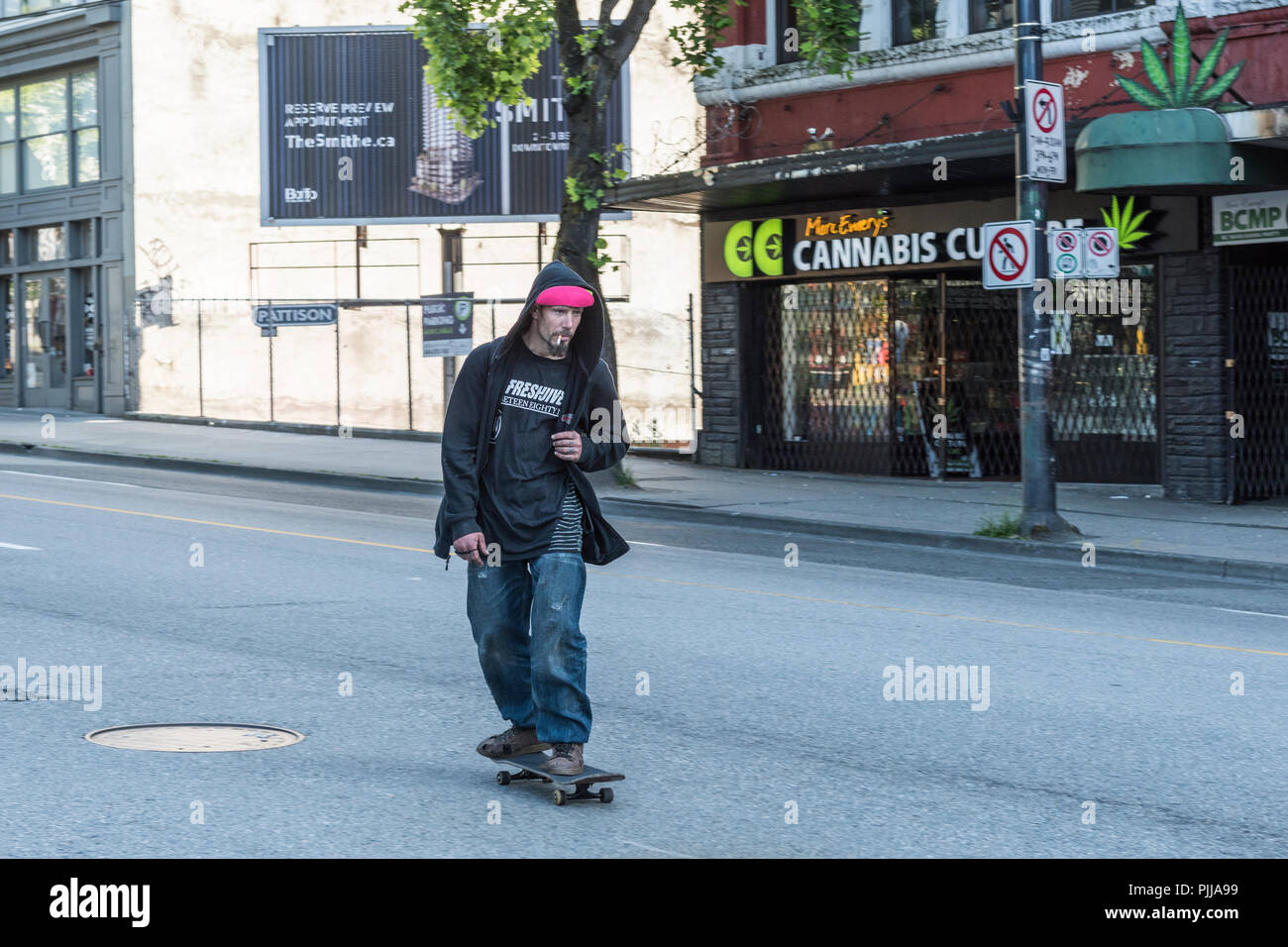 Skate boarder traveling down the middle of a street in the Vancouver Downtown Eastside. Stock Photo