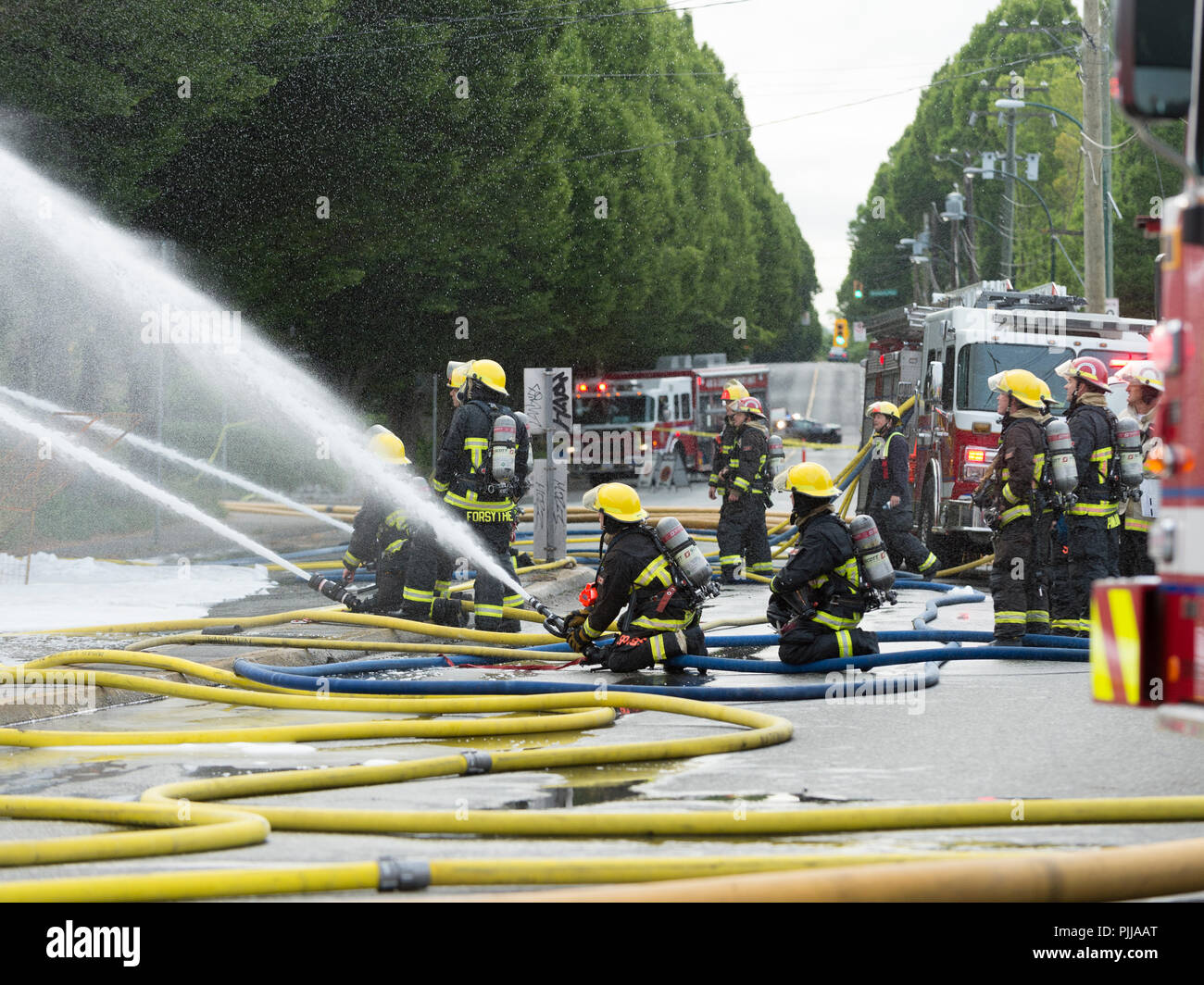 Emergency fire trucks and firemen at the scene of a house fire, Vancouver city. Stock Photo