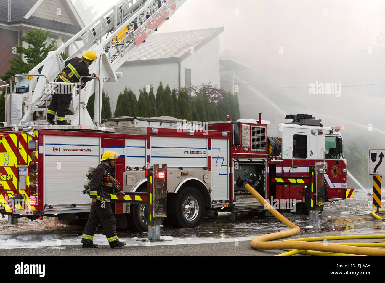 Emergency fire trucks and firemen at the scene of a house fire, Vancouver city. Stock Photo
