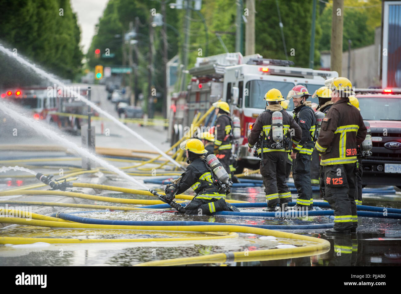 Emergency fire trucks and firemen at the scene of a house fire, Vancouver City, Stock Photo