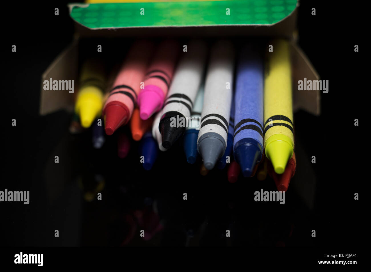 Crayons spilling out of a box. Kids coloring tools. Various colors of children's wax sticks for drawing. Stock Photo