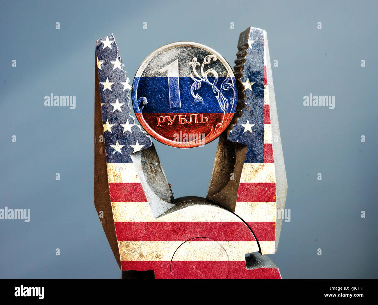 Pliers with USA flag squeezed the ruble with Russian flag. Sanction. Stock Photo