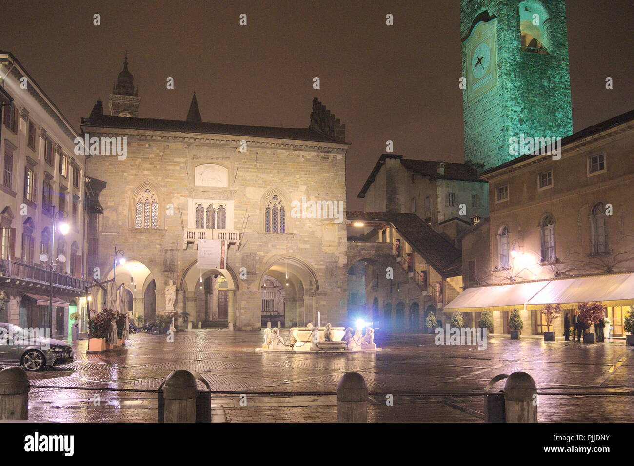 Italy, the historic old town of Bergamo.  The Piazza Vecchia  is lit up on a rainy winters evening Stock Photo