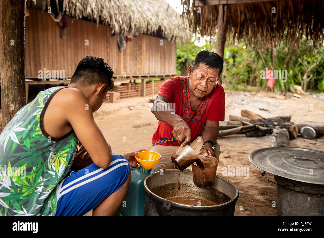 Pucallpa, Peru. 17th July, 2018. A shaman (R) puts a broth of 'Ayahuasca' into a cup. The brew, which is prepared from the liana Banisteriopsis caapi, is used for medical or religious purposes in the Peruvian Shipibo ethnic group and in various Amazonian ethnic groups. Credit: Ana Karina Delgado/dpa/Alamy Live News Stock Photo