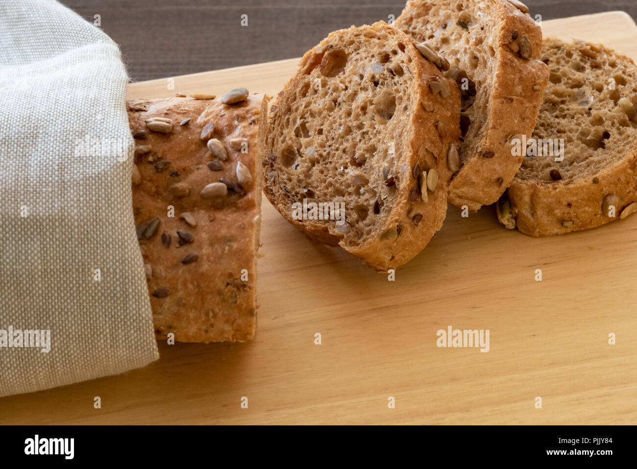 Sliced multi seeded baguette on a bread board. Stock Photo