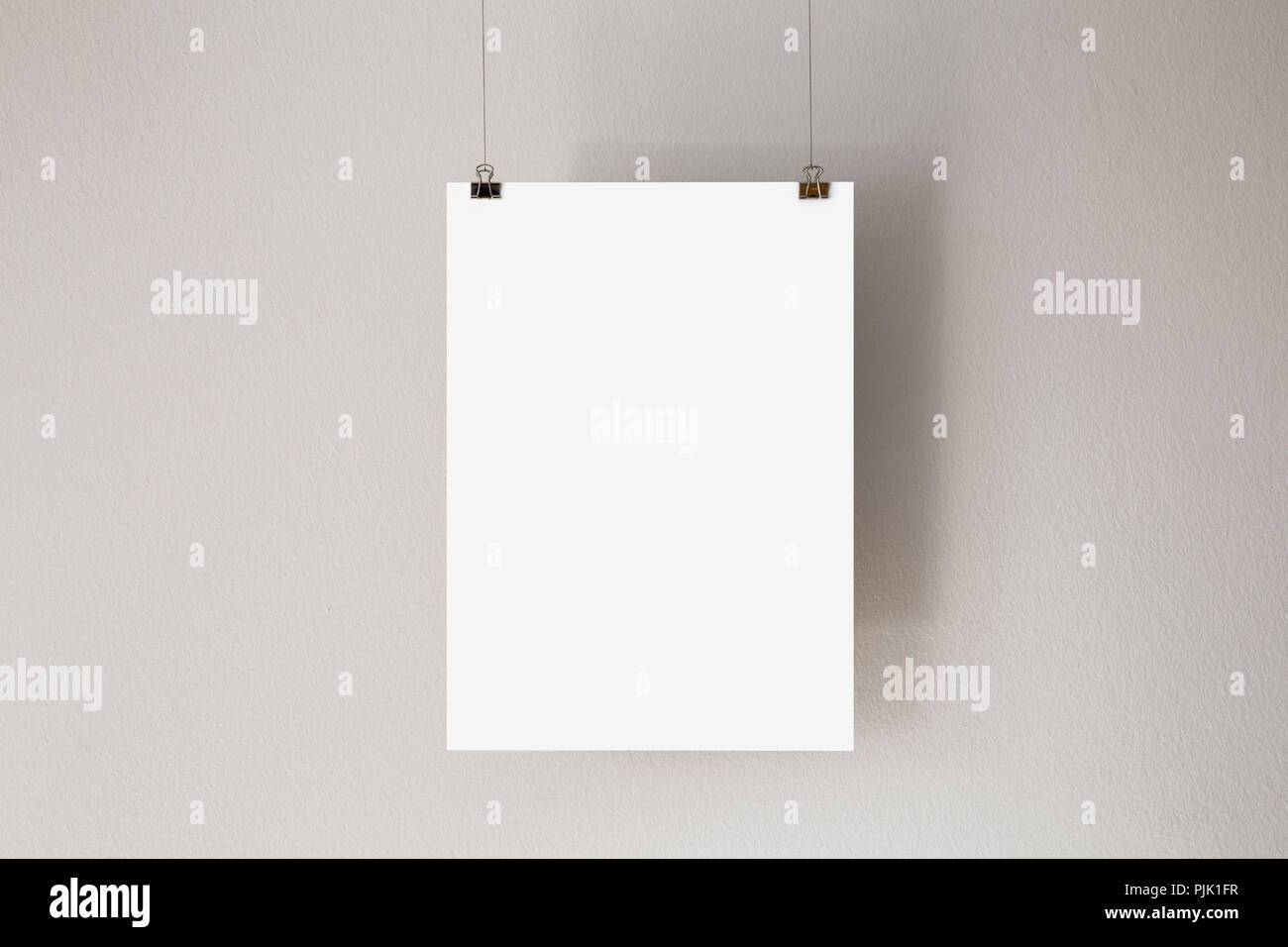 A blank sheet of copy-space paper, hanging from the ceiling Stock Photo