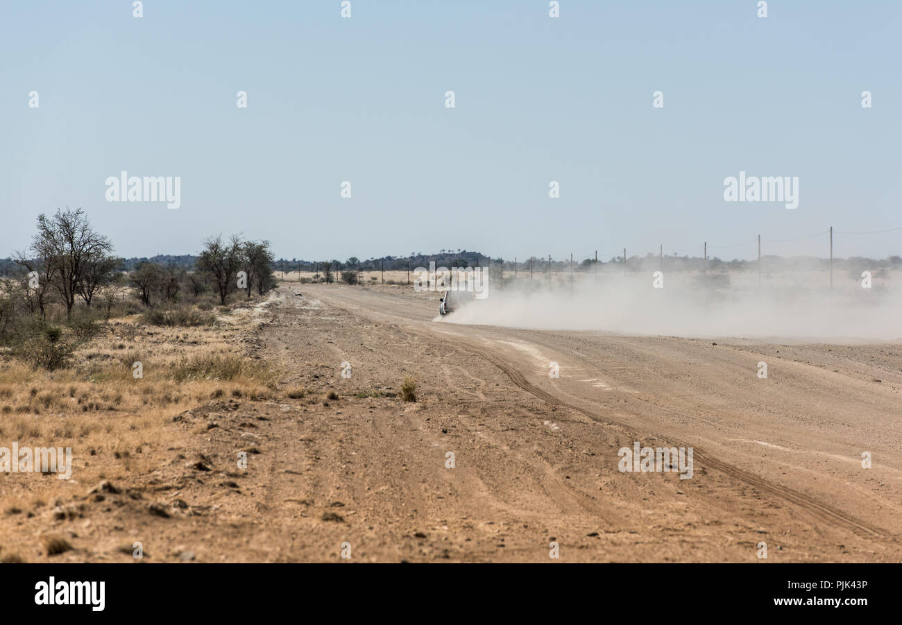 Car leaving dust cloud on a road in Namibia Stock Photo