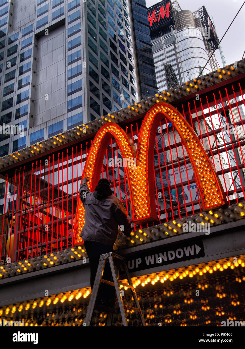 Man changing light bulbs on mc donalds advertisement in manhattan hi