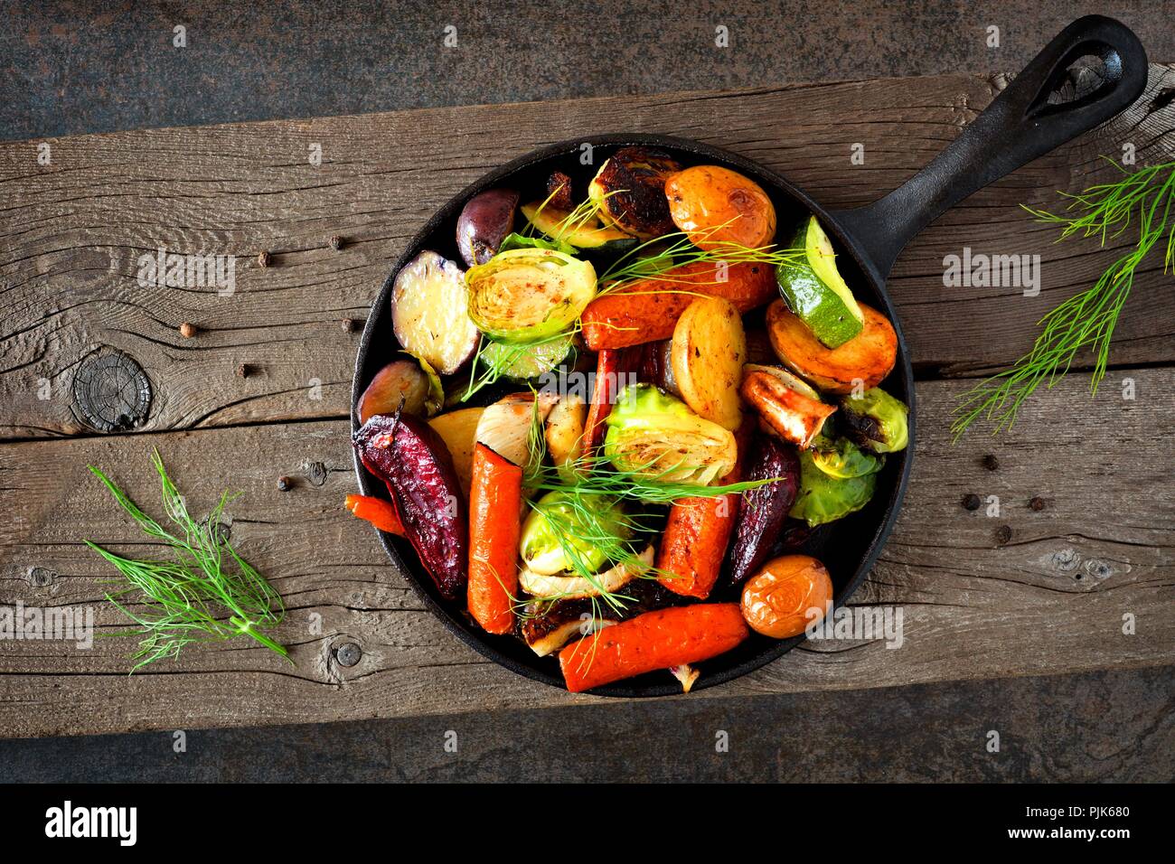 Cast iron skillet of roasted autumn vegetables against a rustic dark