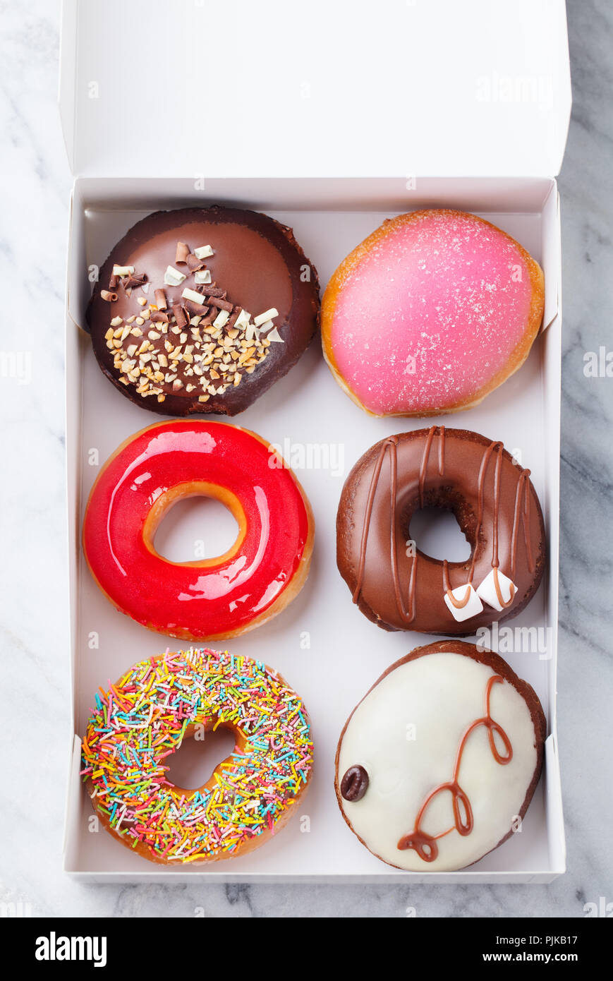 Assortment of donuts in a box on marble table background. Top view ...