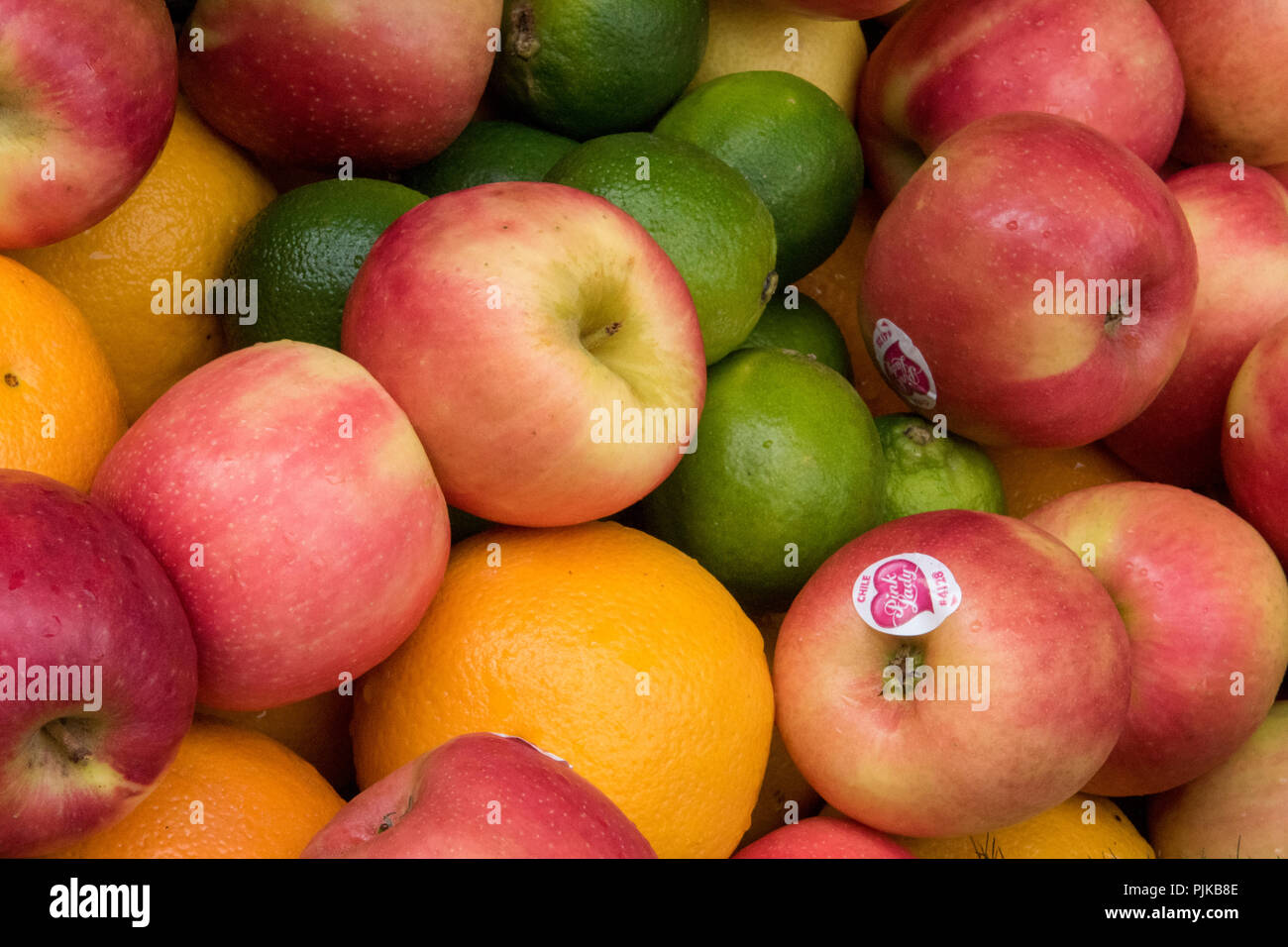 apples, oranges and limes on a fresh fruits and vegetables market stall selling healthy foods. Stock Photo