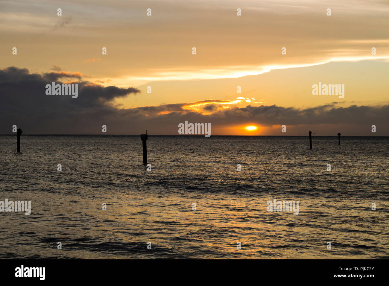 Orange Sunset over Ocean with Pier Pilings Stock Photo