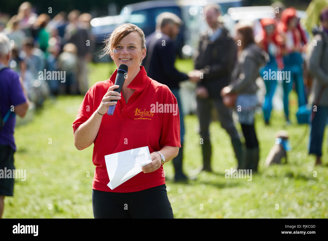 Lady in red t-shirt, holding a microphone and a piece of paper at The Lowland Games, Thorney, Somerset, England Stock Photo
