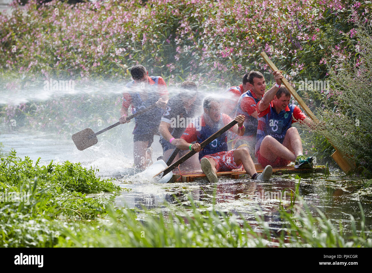 Six men on a raft in a river being sprayed with a hose pipe at The
