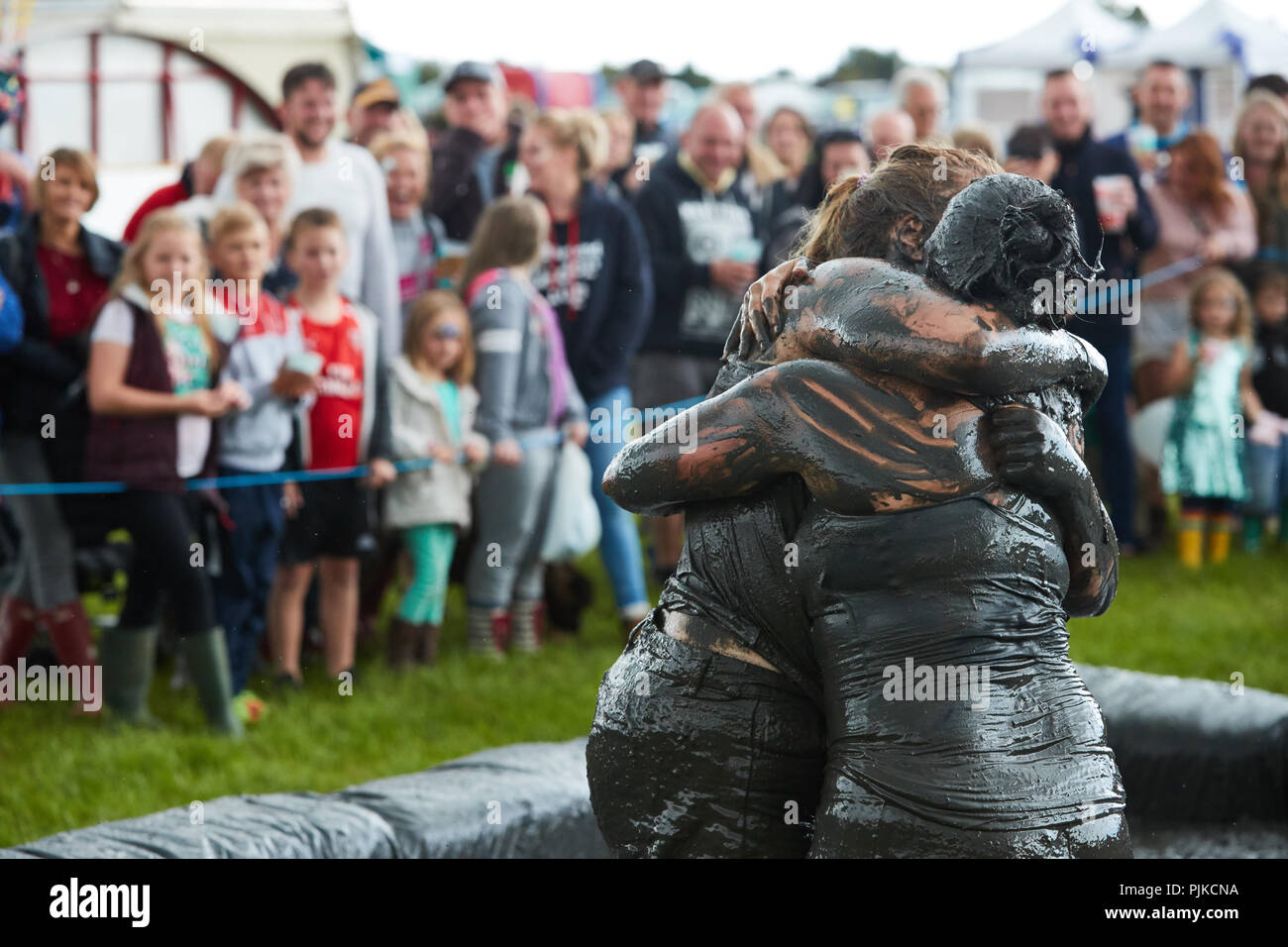 Two women mud wrestling with a crowd behind at The Lowland Games, Thorney, Somerset, England Stock Photo