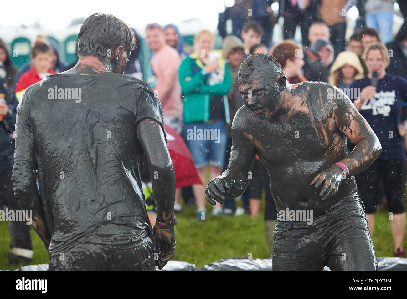 Two men mud wrestling with a crowd behind at The Lowland Games, Thorney, Somerset, England Stock Photo
