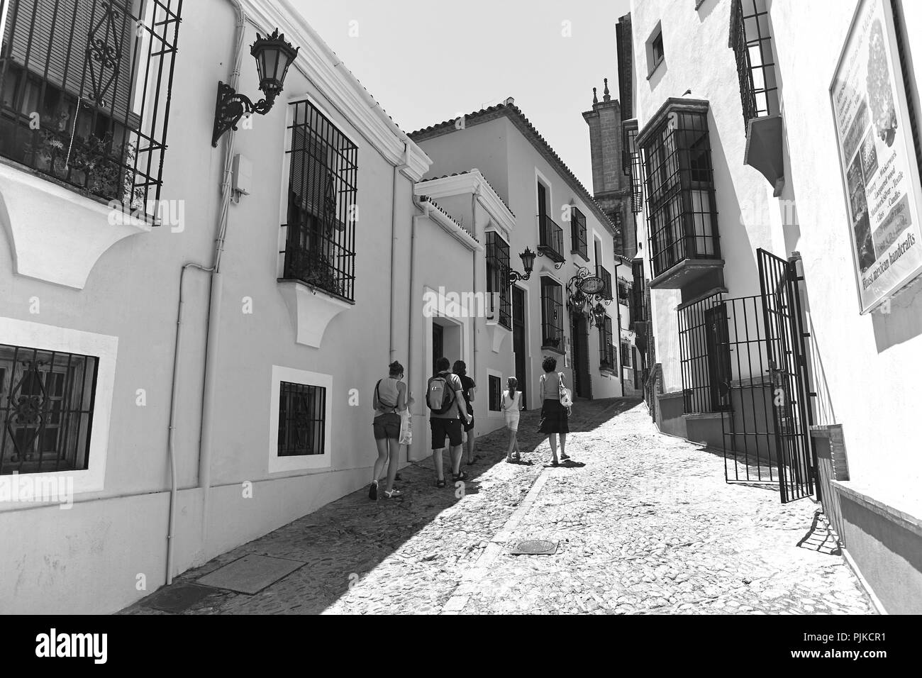 A family walk in sandals up a narrow cobbled street on a sunny day in Ronda Andalusia Spain Stock Photo