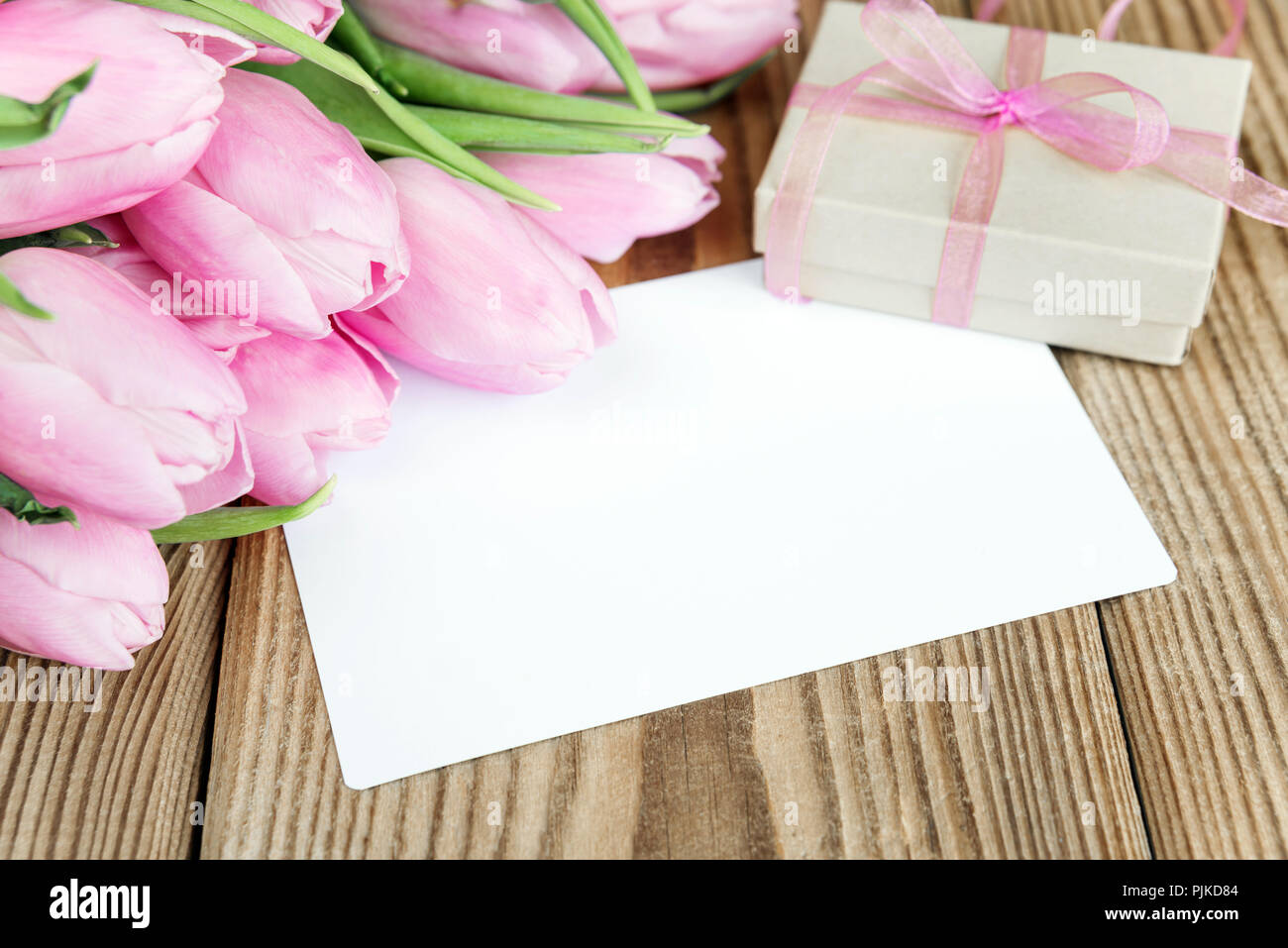 Tulips flowers, empty greeting card and gift box with a bow on a background of old wooden boards Stock Photo