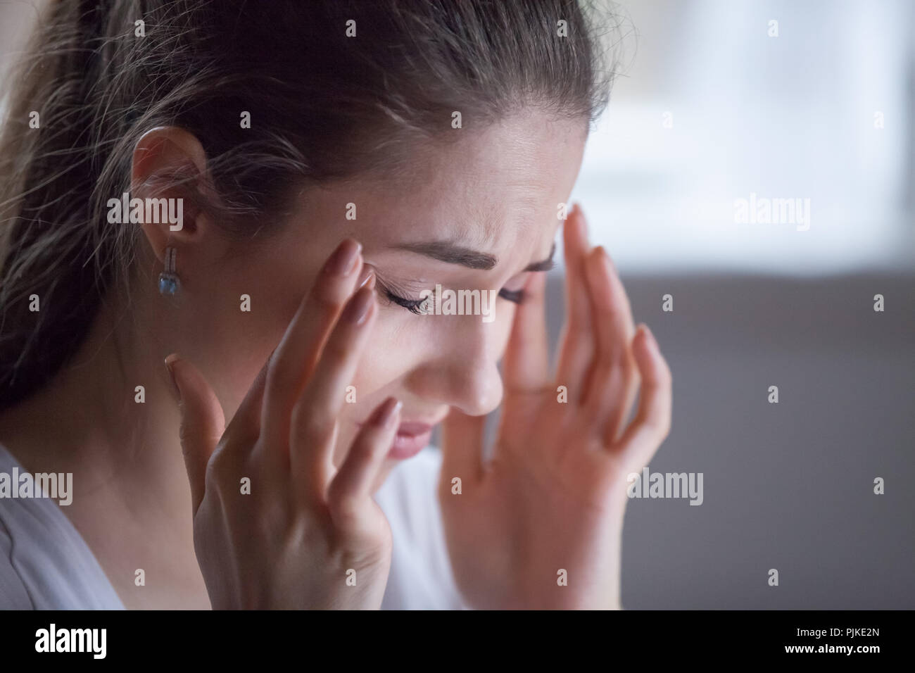 Close up of exhausted female suffering from headache  Stock Photo